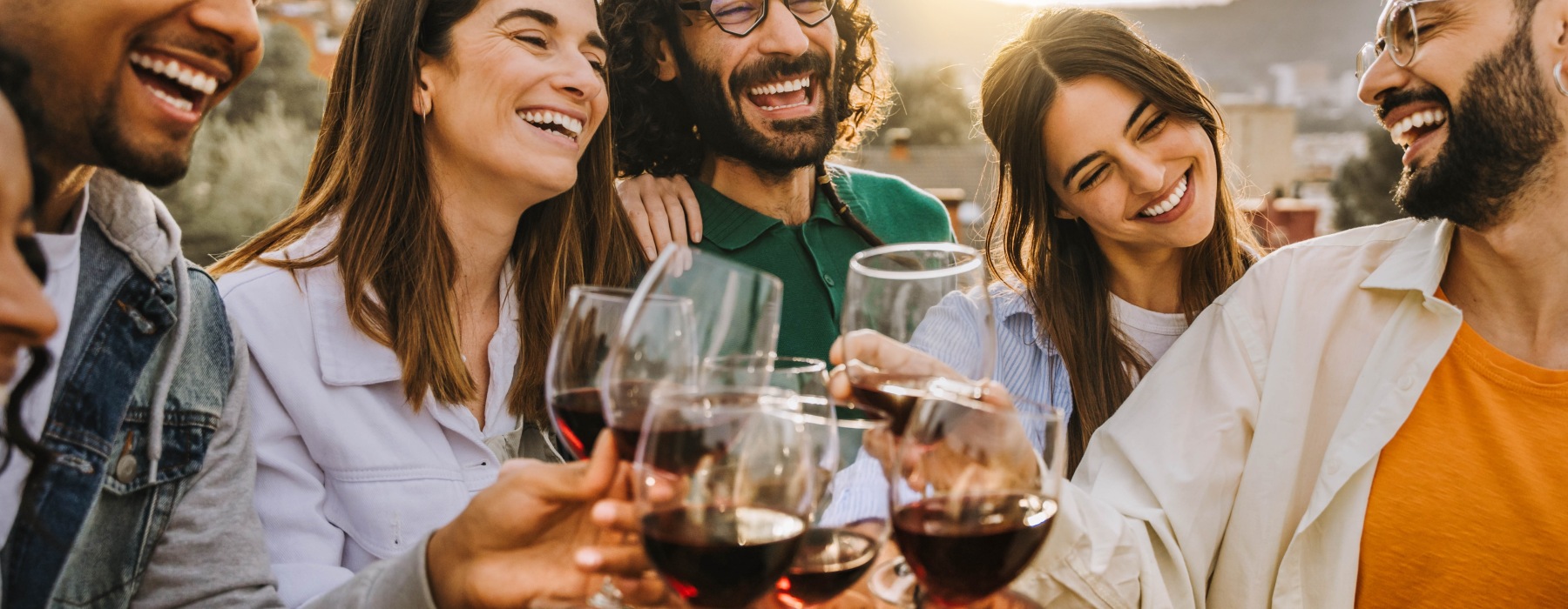 Friends laughing as they hold glasses of red wine